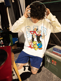 Person dressed in white baggy tee and jorts listening to music on headphones