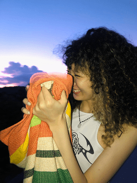 Chinese student smiling hugging toy on sunset background