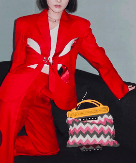 Close up editorial shot of model wearing a bright red suit leaning on sofa