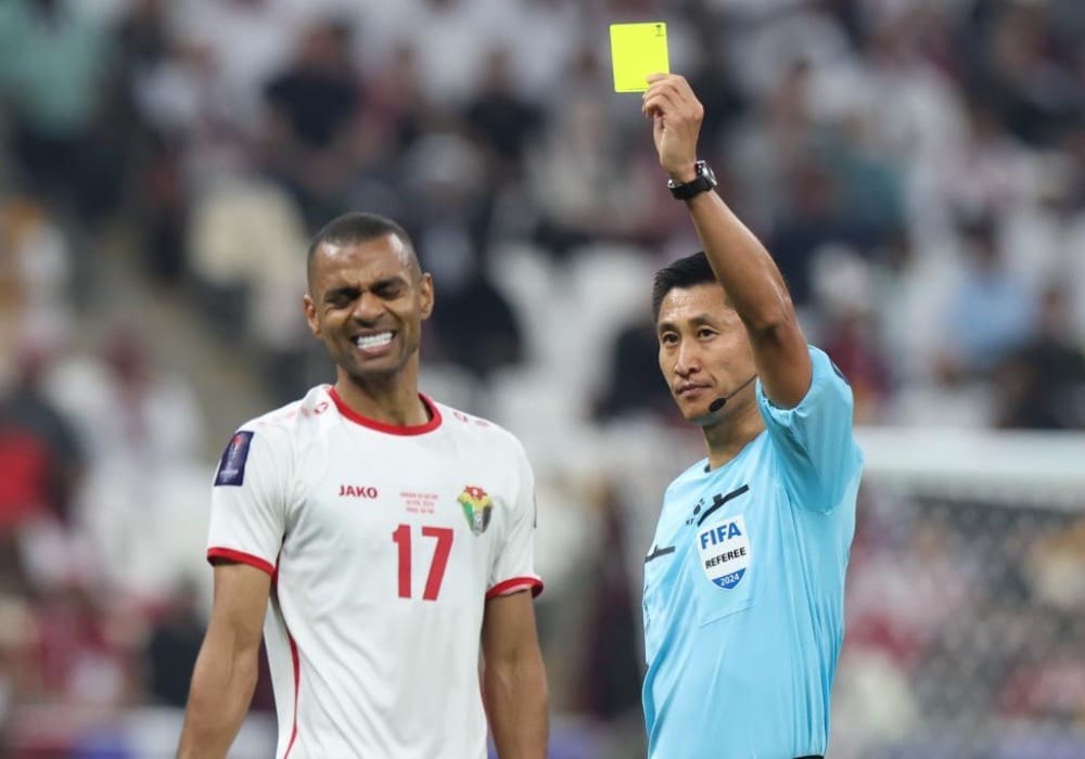 Ma ning referee showing yellow card next to smiling football player at world cup 2026