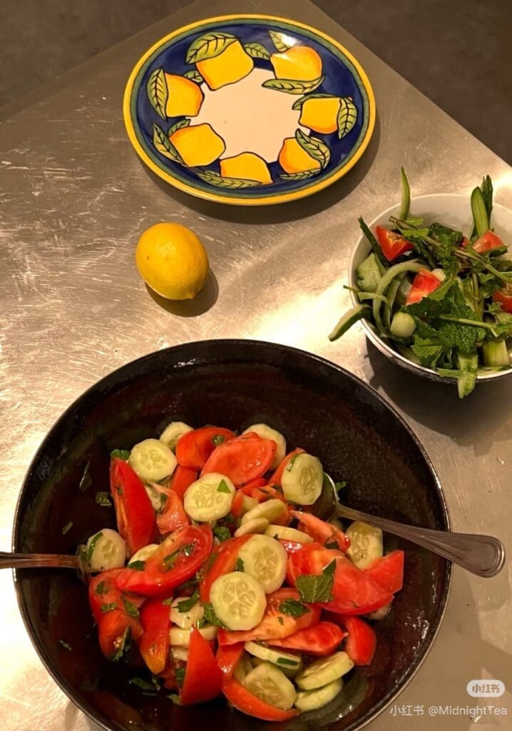 Two salad bowls and an empty lemons-decorated plate on steel table