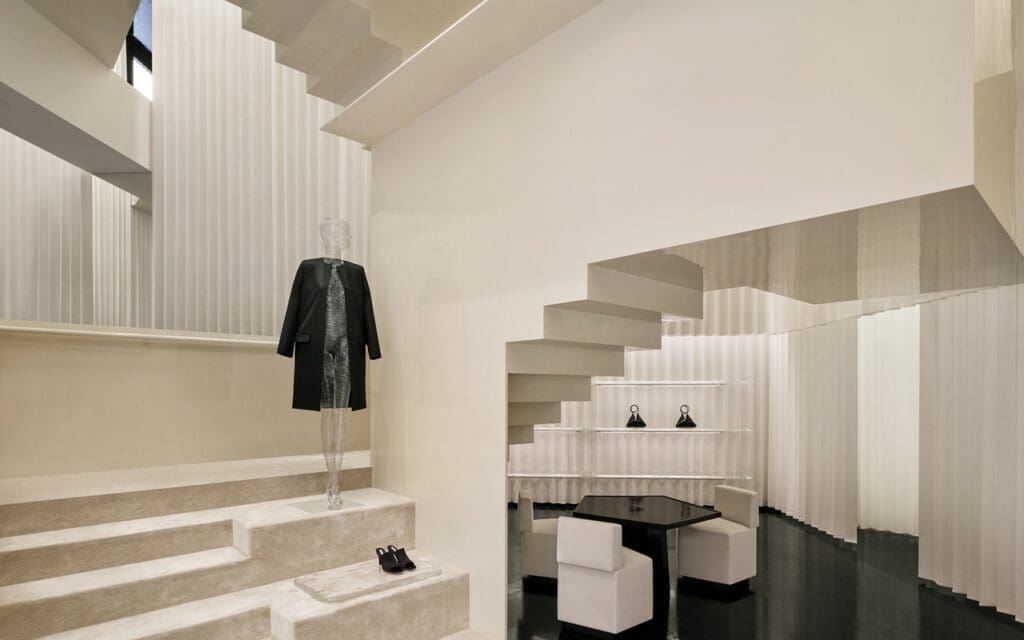 Minimalistic scandinavian Toteme store in shanghai with beige walls and black coat on mannequin